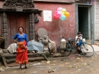Nepal, Central Region, Bagmati Zone, Kathmandu, Tengan: A woman is waiting close to the Naradevi temple for the end of the  Gai Jatra festival to start her business selling vegetables, while the balloon seller seems to be frustrated of his business of the day.