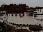 Tibet, Lhasa, Potala Square: The Potala from the square with cloudy sky, the meaning of the banners is unknown