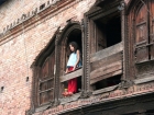 Nepal, Central Region, Bagmati Zone, Kathmandu, Teku: Girl in the window of an old house at the Bagmati river banks